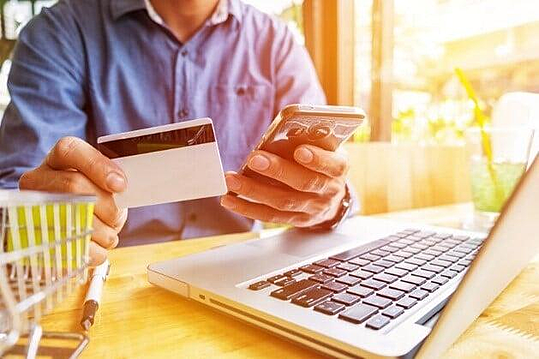 Une personne tenant une carte bancaire et un smartphone, pour payer une transaction